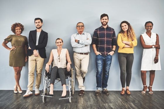 A diverse group of 7 potential employees lined up against a wall