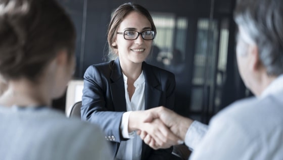 A seated female lawyer shaking hands with a man seated next to a woman